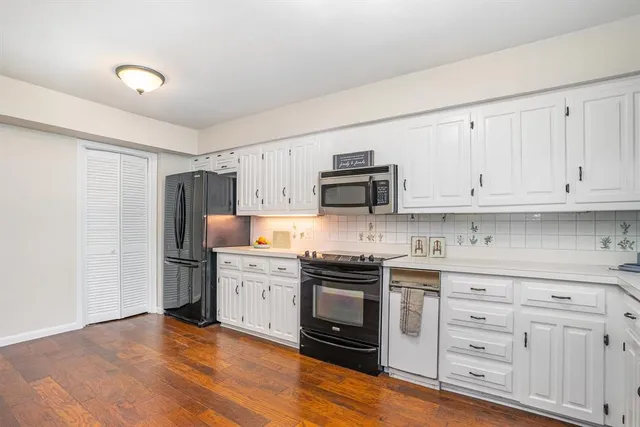 a kitchen with stainless steel appliances granite countertop a stove top oven a sink dishwasher and a refrigerator with wooden floor