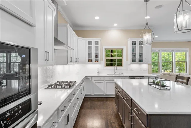 a kitchen with stainless steel appliances granite countertop a stove top oven a refrigerator a sink and a dining table with wooden floor