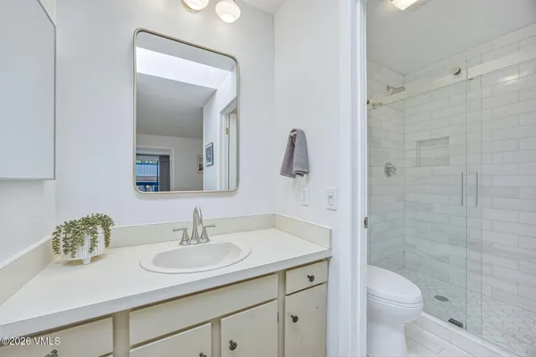 a bathroom with a granite countertop toilet a sink a mirror and shower