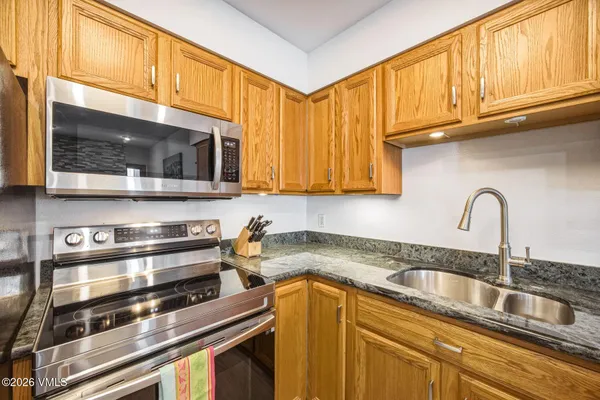 a kitchen with stainless steel appliances granite countertop a sink a stove microwave and cabinets