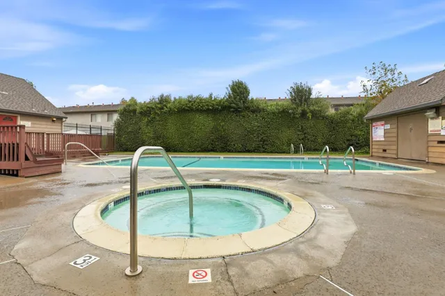 a backyard of a white house with potted plants and a large tree