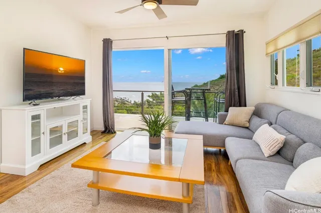 a living room with furniture a flat screen tv and a floor to ceiling window