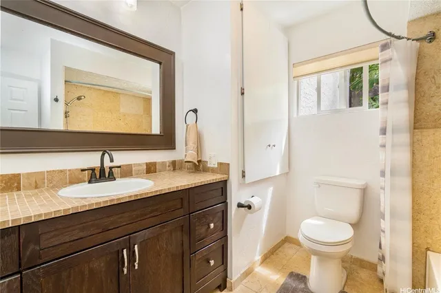 a bathroom with a granite countertop toilet sink and mirror