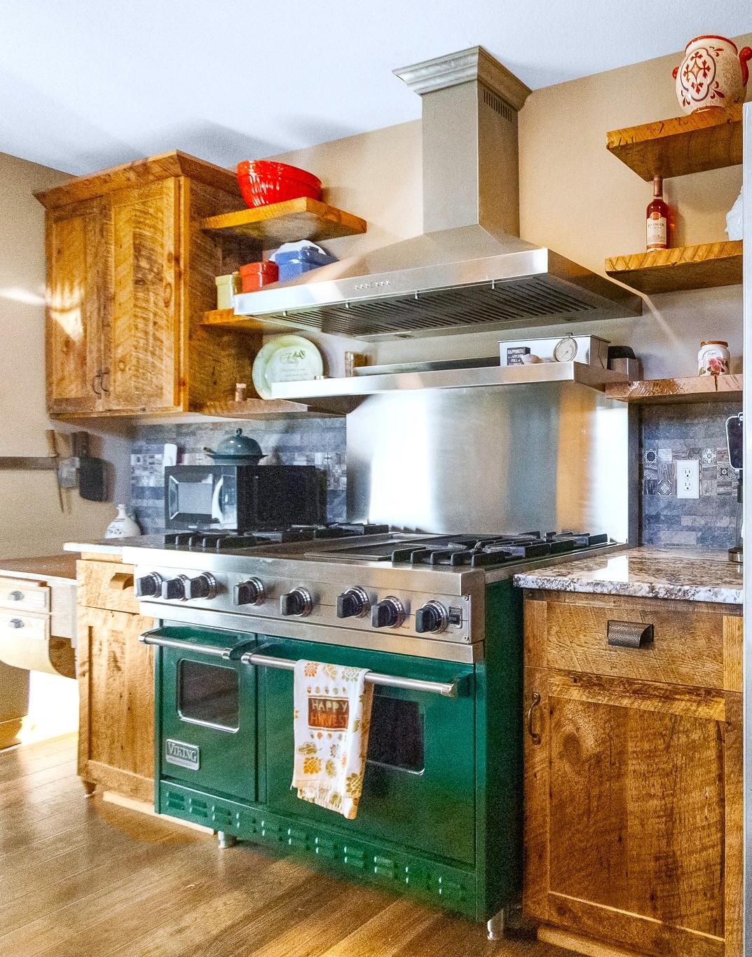6014 Brown Road Kettle River, MN 55757 - Photo 15 of 54 Kitchen featuring open shelves, wall chimney range hood, range with two ovens, brown cabinetry, and light wood-style flooring