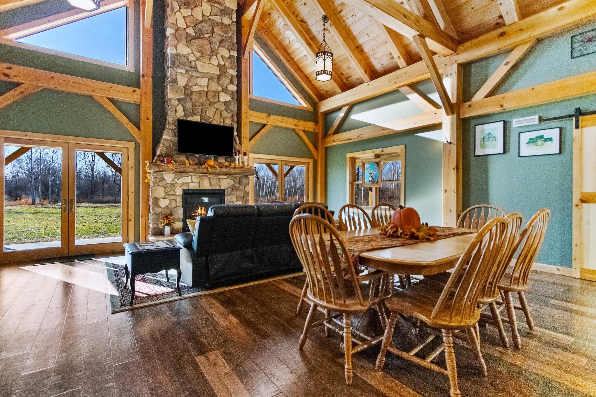 6014 Brown Road Kettle River, MN 55757 - Photo 8 of 54 Dining space with a fireplace, high vaulted ceiling, hardwood / wood-style floors, a barn door, and french doors