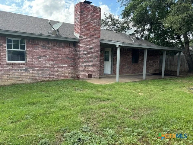 a view of a house with brick walls and a yard with a large tree
