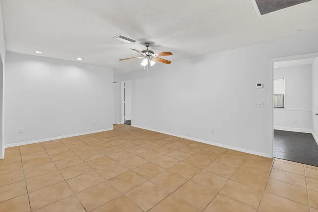 an empty room with wooden floor fan and windows