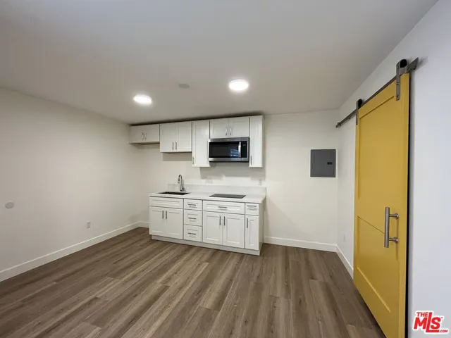 a kitchen with a sink a stove top oven and wooden floor