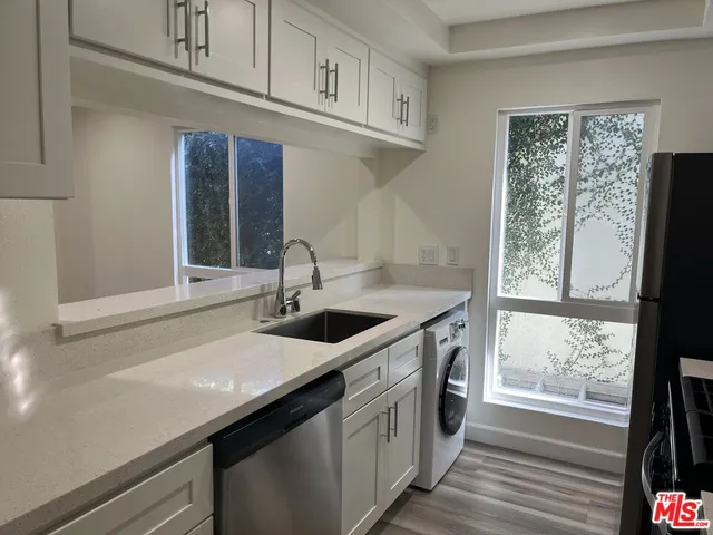 a kitchen with stainless steel appliances granite countertop a sink and a large window