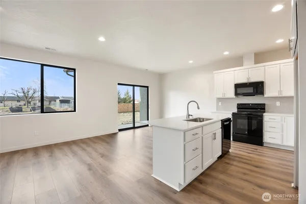 a large kitchen with stainless steel appliances granite countertop a sink a stove a microwave a center island and cabinets