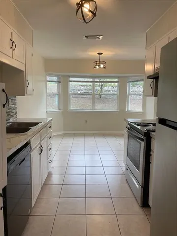 a kitchen with granite countertop a stove a sink and a refrigerator