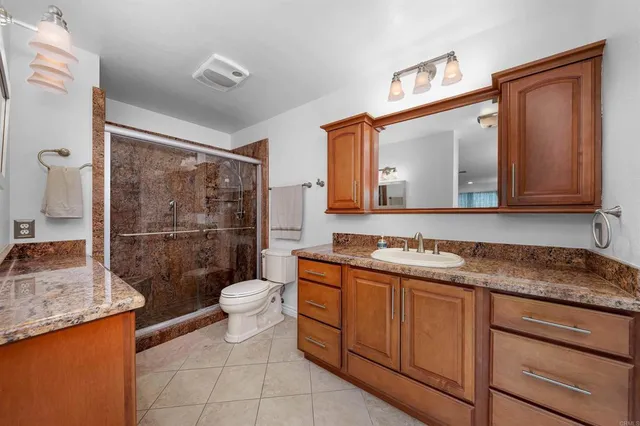 a bathroom with a granite countertop sink toilet and shower
