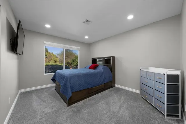 a spacious bedroom with a bed and a flat screen tv