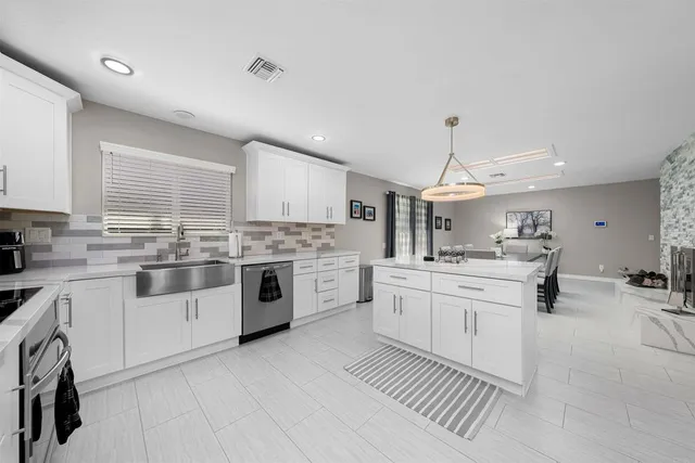 a kitchen with stainless steel appliances a white cabinets and wooden floor