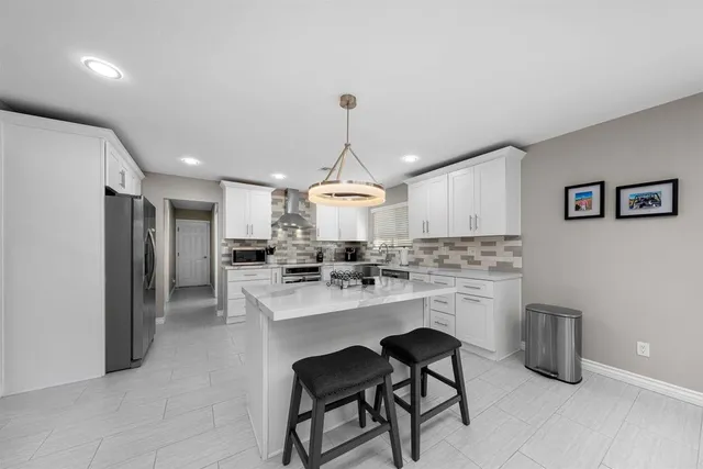 a kitchen with kitchen island a stove a chandelier and a refrigerator
