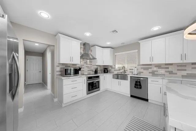 a kitchen with granite countertop white cabinets and stainless steel appliances