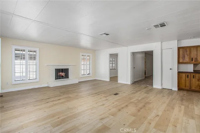 a view of an empty room with window and wooden floor