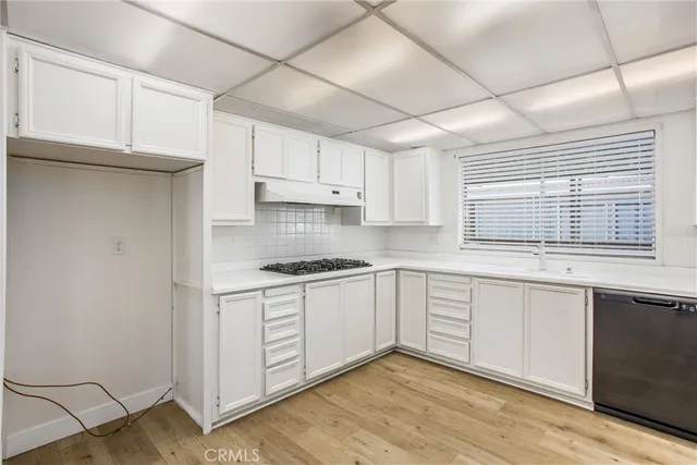 a kitchen with stainless steel appliances granite countertop a stove a sink and white cabinets