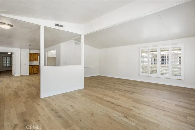 a view of a big room with wooden floor and windows