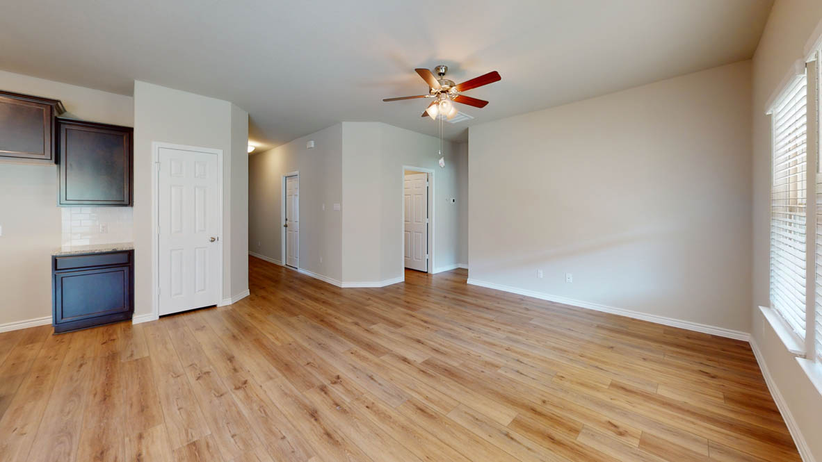 429 Creekfall Road Burnet, TX 78611 - Photo 10 of 28 Laminate flooring extends throughout this open-concept room, illuminated by a multi-bladed ceiling fan and natural light.