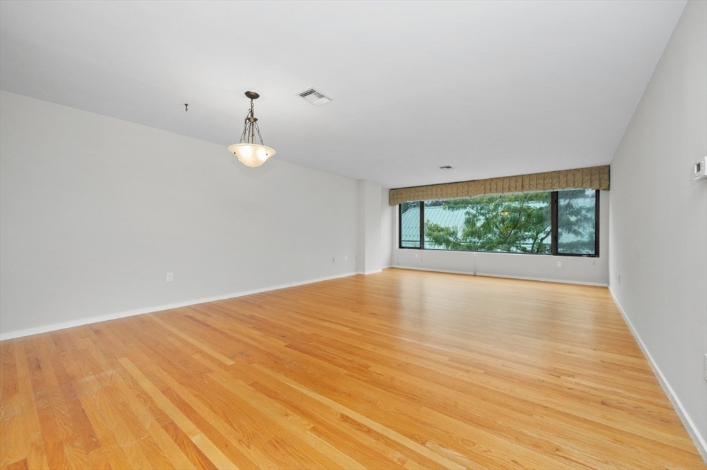 183 Oak Street, Unit 307 Newton, MA 02464 - Photo 6 of 24 an empty room with wooden floor and windows