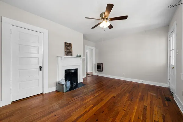 a view of empty room with wooden floor and fan