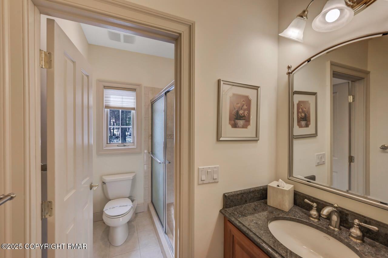235 Wolf Hollow Road Lake Harmony, PA 18624 - Photo 72 of 98 a bathroom with a granite countertop toilet a sink and a mirror