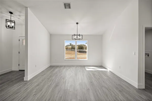 an empty room with wooden floor a exposed radiator and a window