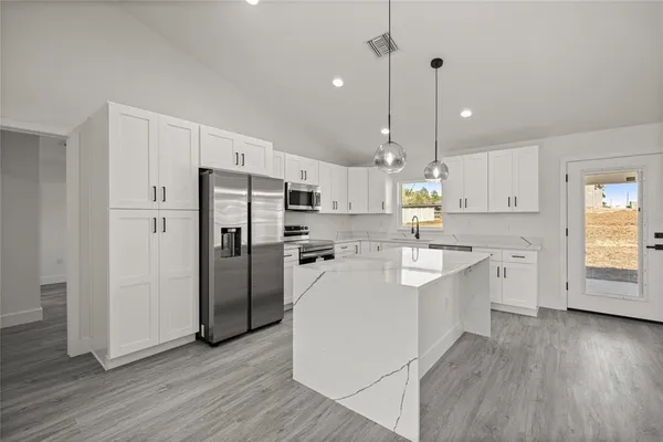 a large kitchen with white cabinets and stainless steel appliances