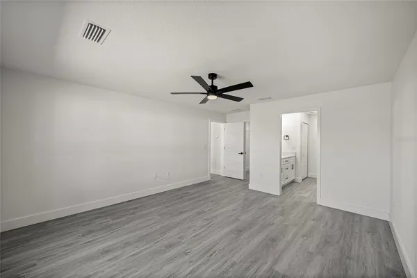 an empty room with wooden floor a ceiling fan and windows