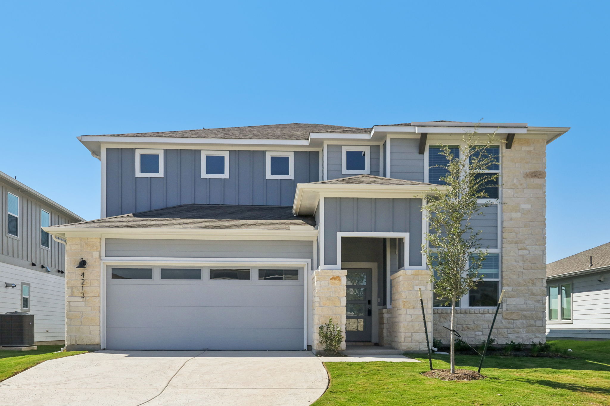 View of front of home featuring stone siding, board and batten siding, roof with shingles, and a front yard