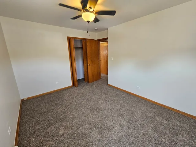 an empty room with closet and a chandelier fan
