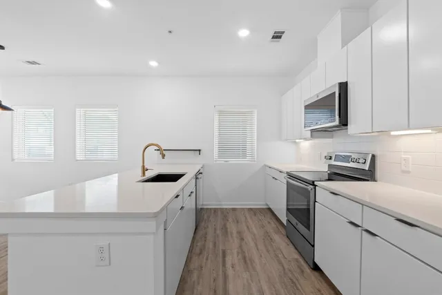 a kitchen with a sink a stove and cabinets