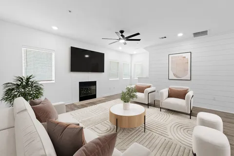 a living room with furniture a flat screen tv and a ceiling fan