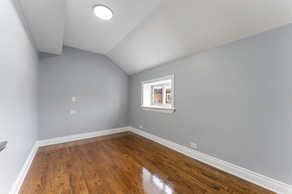 1215 North Harding Avenue, Unit 2 Chicago, IL 60651 - Photo 4 of 10 an empty room with wooden floor and windows