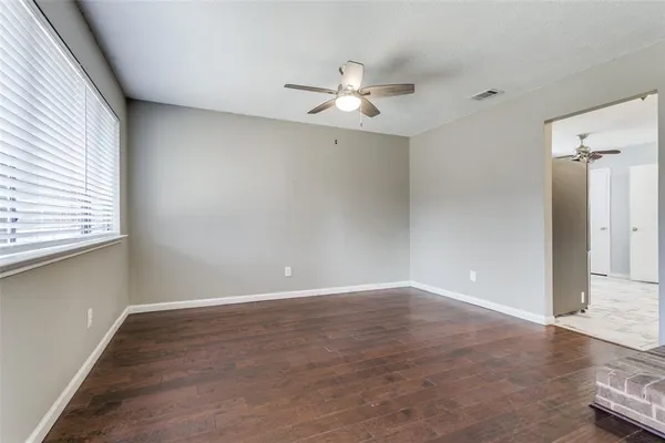 an empty room with wooden floor fan and windows