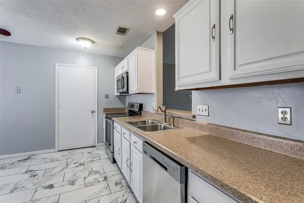 a kitchen with granite countertop a sink a stove and cabinets