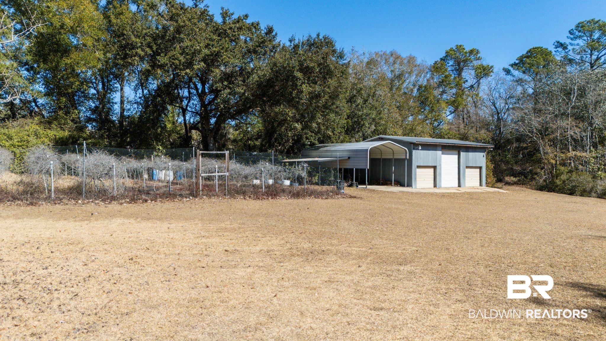 32989 Antietam Road Lillian, AL 36549 - Photo 36 of 56 View of yard with a detached garage, view of wooded area, and an outdoor structure