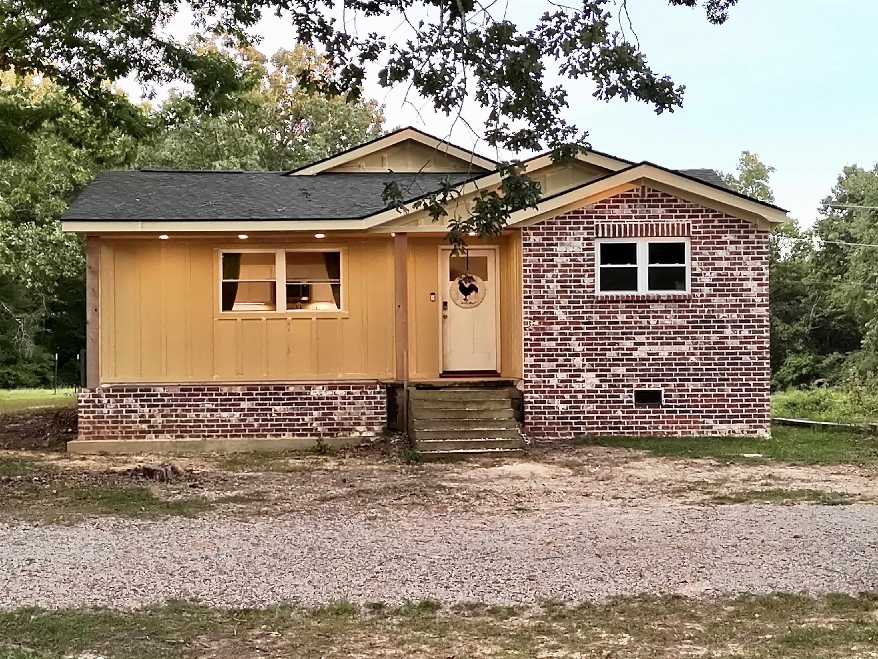 Brick and board and batten siding exterior with a dark shingle roof