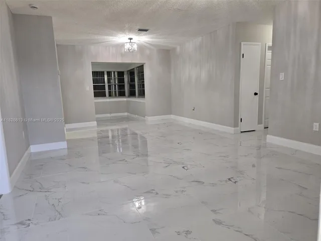 an empty room with windows and fireplace