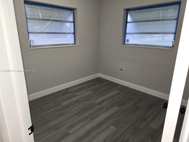 an empty room with wooden floor and cabinet