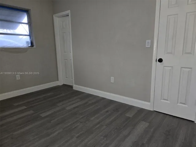 a view of an empty room with wooden floor and closet