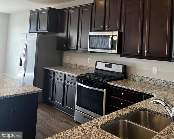 a kitchen with granite countertop wooden cabinets and stainless steel appliances