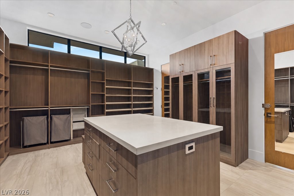 657 Ridgestone Rim Court Henderson, NV 89012 - Photo 38 of 97 Custom wood cabinetry and a central stone-topped island define this organized closet space.