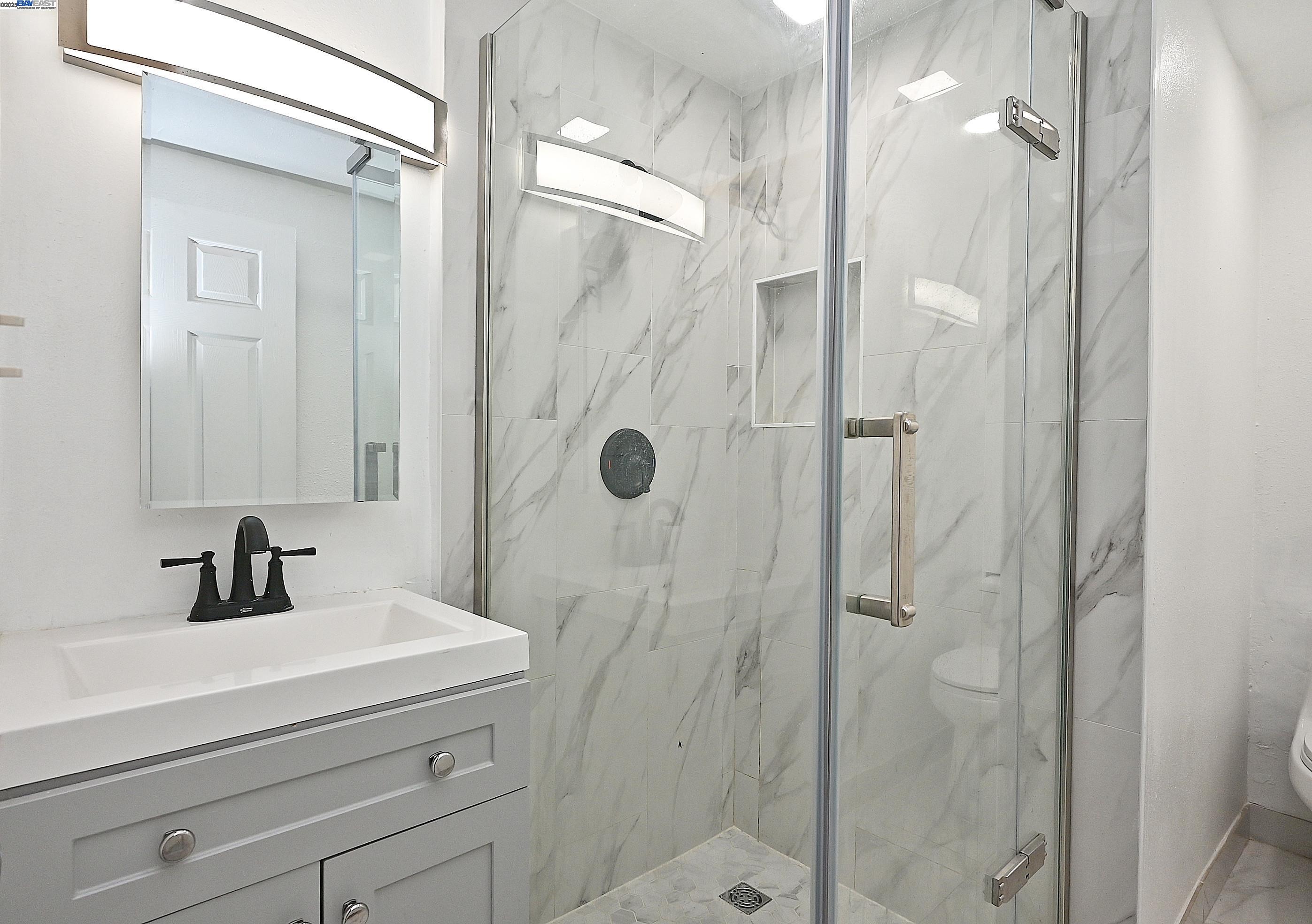 19092 Ricardo Avenue San Lorenzo, CA 94541 - Photo 24 of 29 a bathroom with a sink a mirror a glass door and shower