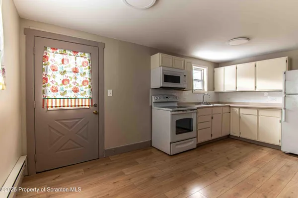 a white kitchen with a window and stainless steel appliances