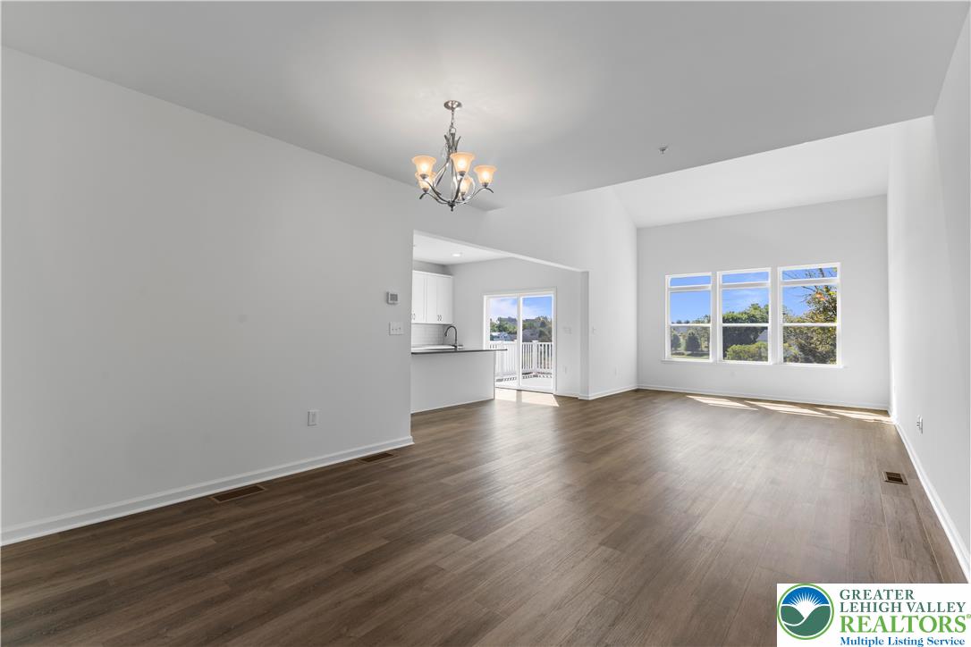 93 Timber Trail, Unit 46 Easton, PA 18045 - Photo 4 of 26 an empty room with wooden floor chandelier and windows