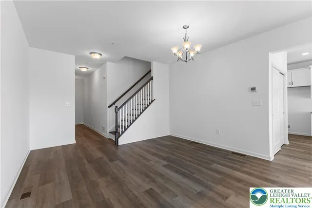 a view of an empty room with wooden floor and stairs