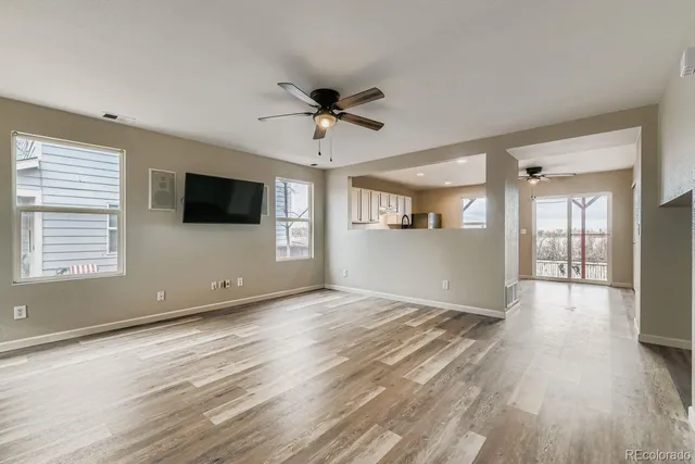 a view of an empty room with a window and wooden floor