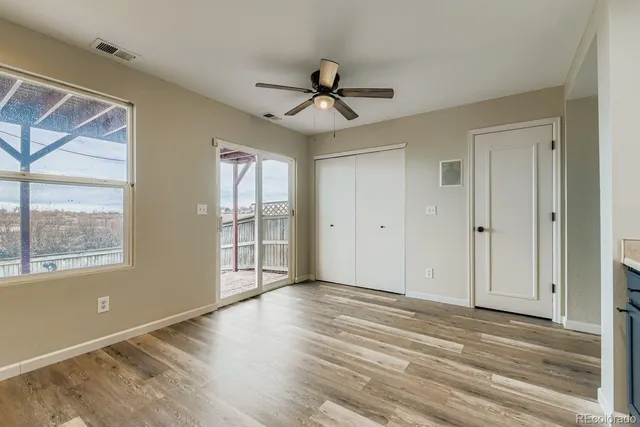 an empty room with wooden floor fan and windows